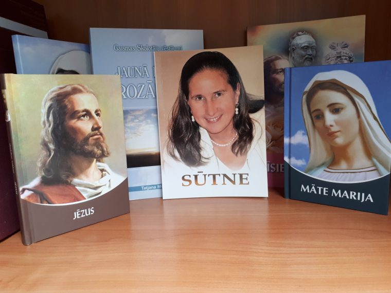 Uz galdā izvietotās vairākas dažādas grāmatas par kristietību ("Jēzus", "Māte Marija", "Sūtne")