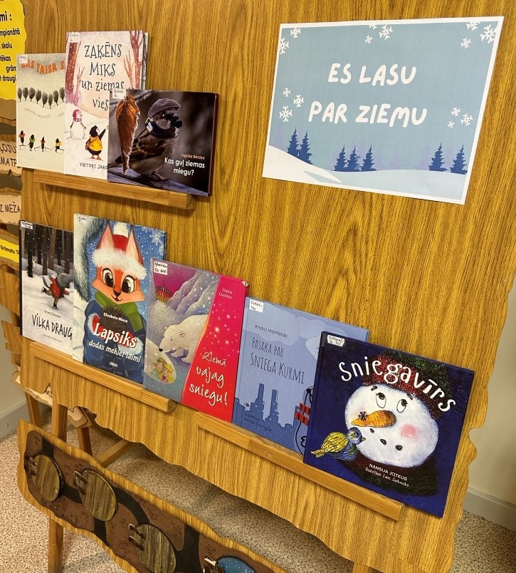Uz koka stenda izliktās dažādās grāmatas bērniem par sniegu