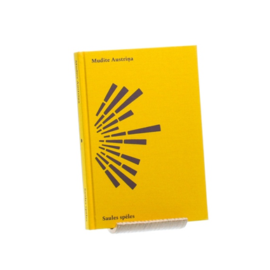Dzeltenās krāsas grāmatas vāki M.Austriņas darbu izlasi “Saules spēles”. No sānā pusaplī brūnās svītras dažādā lielumā.